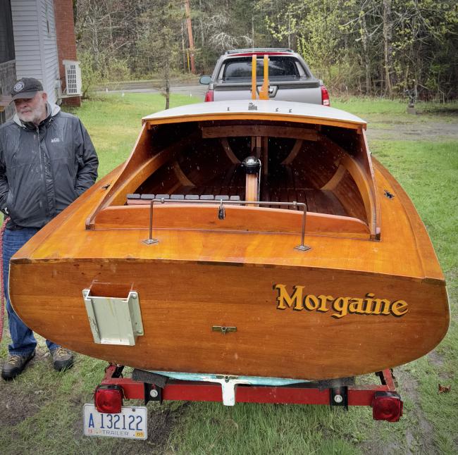 Gaff rigged wooden sailboat with trailer, view of boat on trailer from stern