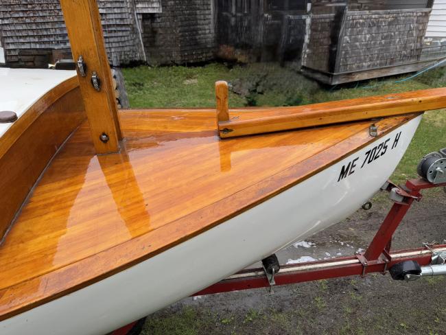 Gaff rigged wooden sailboat with trailer, up close starboard bow view