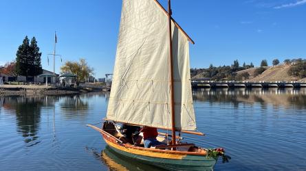 Dory with the sail raised on glassy water