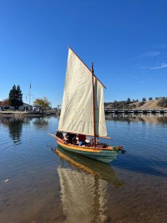 Dory with the sail raised on glassy water