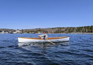 17' LOA Cape Split Peapod, in water being rowed