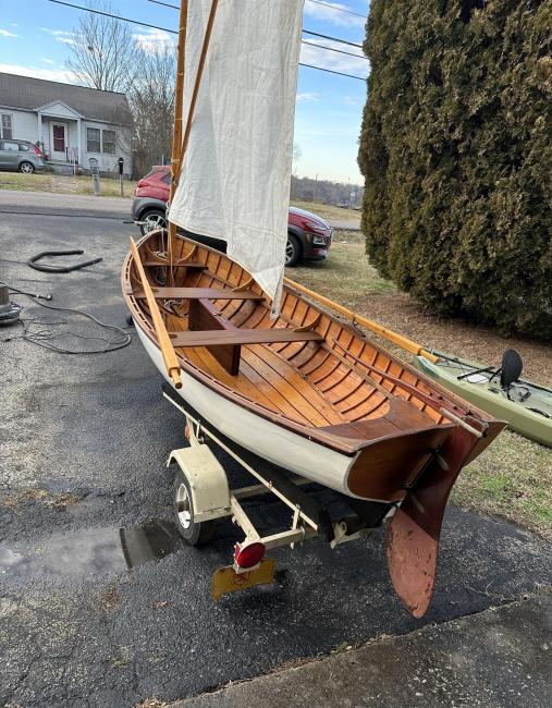 Cats paw dinghy row and sail, on trailer, stern port side view