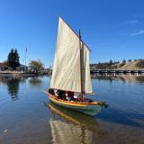 Dory with the sail raised on glassy water