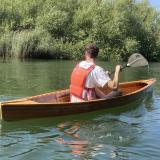 Tom paddling down a river, backdropped by trees. 